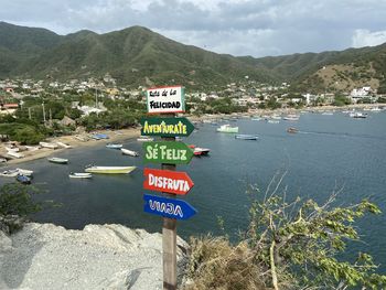 Information sign by sea against sky