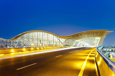 Light trails on road in city against blue sky