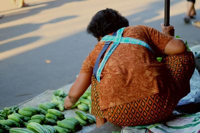 Rear view of woman selling cucumbers on street