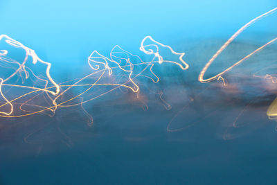 Close-up of light trails against blue sky