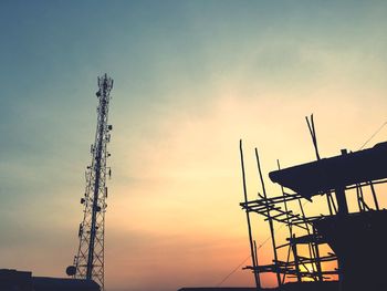 Low angle view of silhouette communications tower against sky during sunset