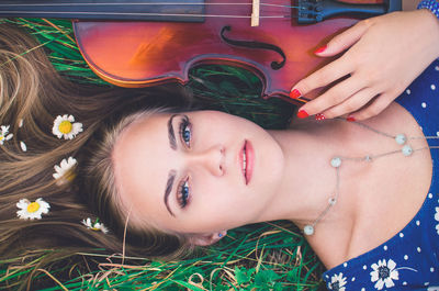 High angle view of woman lying down on grass with guitar outdoors