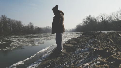 Man standing by river during winter