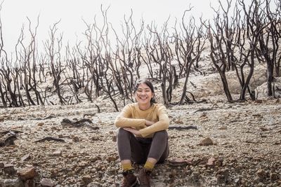 Portrait of smiling young woman sitting on land