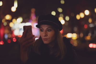 Portrait of man holding smart phone at night