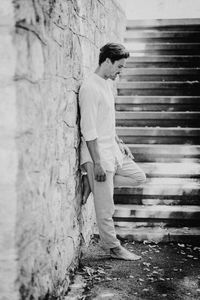 Side view of man leaning against tree trunk