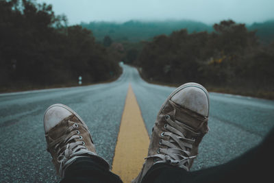 Low section of man wearing shoes on road