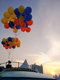 Low angle view of balloons against sky during sunset