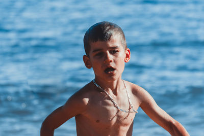Shirtless boy walking against sea