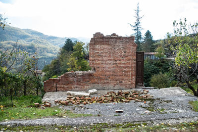 Stone wall by building against sky