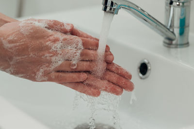 Cropped hand washing hands in sink