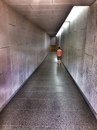 Rear view of person walking in illuminated tunnel