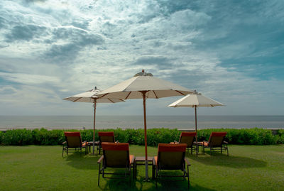 Empty chairs on beach against sky