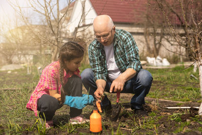 Girl with grandfather gardening on sunny day