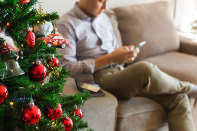 Man using phone while sitting on sofa during christmas