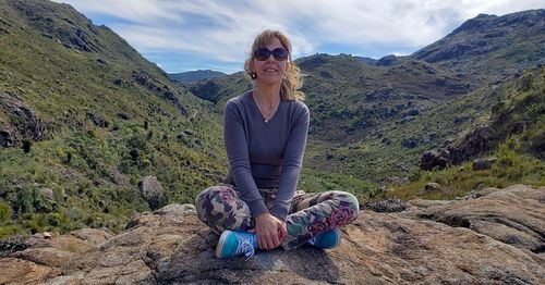 Woman sitting on rock against mountain