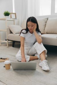 Young woman sitting on sofa at home