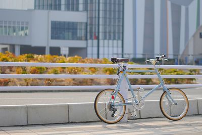 Bicycle parked by railing against building