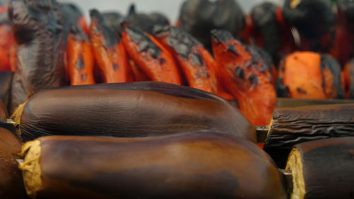 Close-up of eggplants roasted over charcoal in a charcoal grill. red peppers and tomatoes