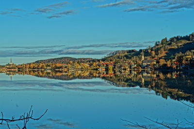 Houses and trees reflecting in lake against sky
