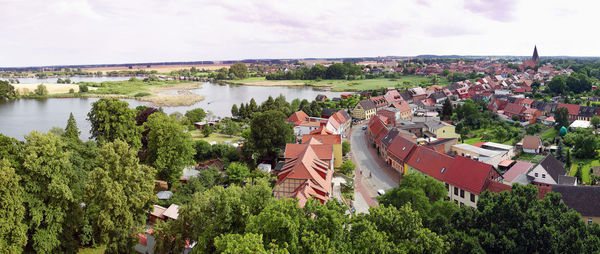Panoramic view of town by river against sky