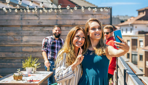 Portrait of smiling friends standing against wall