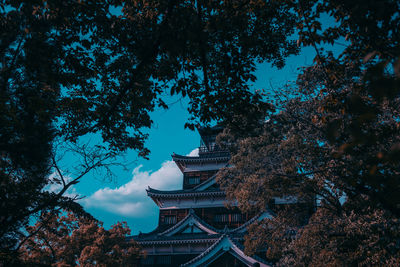 Low angle view of trees and building against sky