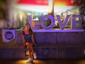 Portrait of young woman standing on steps at night