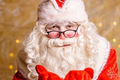 Portrait of santa claus in glasses looking at camera against background