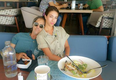 Smiling young woman eating food while sitting on table