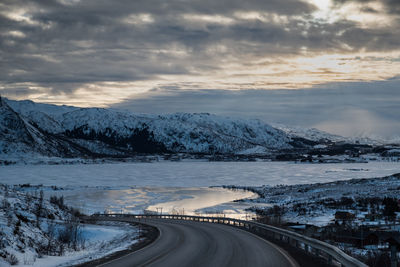 Road by mountains against sky during winter