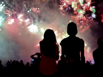 Rear view of silhouette people standing against firework