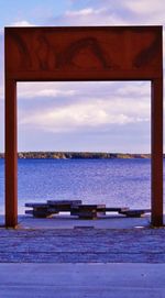 Pier on sea against cloudy sky