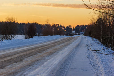 Snow covered landscape against sky during sunset