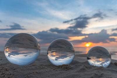 Close-up of crystal ball on beach against sky during sunset