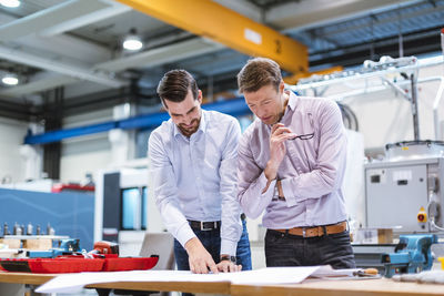 Two men in factory looking at plan