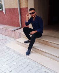 Young man wearing sunglasses sitting on staircase