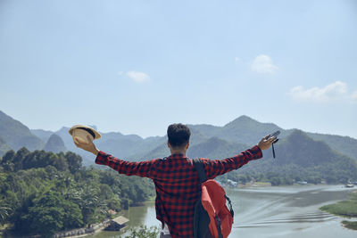 Rear view of man standing on mountain against sky