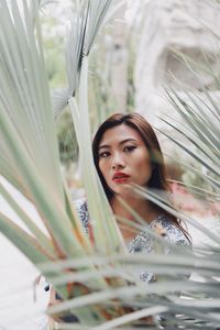 Portrait of young woman standing against plants in park