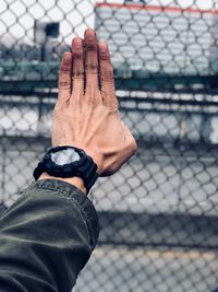 Midsection of man holding chainlink fence