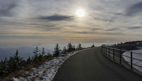 Road amidst snow against sky during sunset