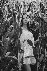 Portrait of young woman standing amidst plants