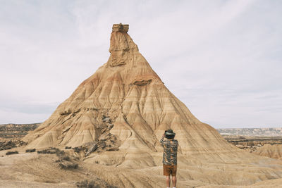 Rear view of man standing on rock against sky