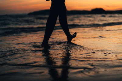 Low section of man walking on sand at beach