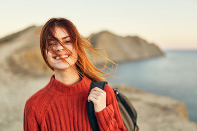 Portrait of smiling young woman standing on beach
