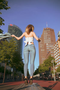 Full length of woman levitating against buildings in city