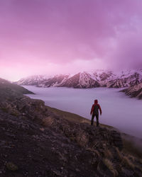 Rear view of man standing on mountain against sky