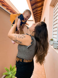 A mother lifts a five-month-old baby dressed as a superhero.