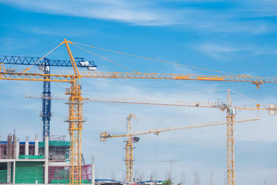 Cranes at construction site against sky