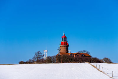 Lighthouse against clear blue sky during winter